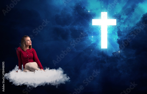 Woman sitting on a cloud looking at a cross