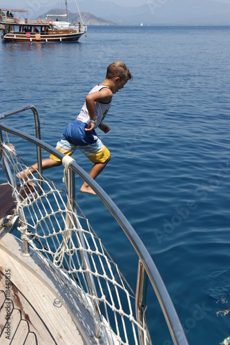 A young boy jumping from a boat to his father in the sea while on vacation, 2016