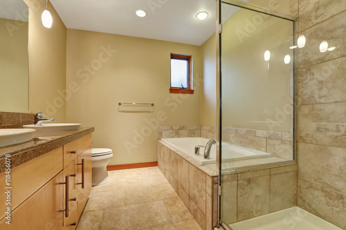 Bathroom interior in beige tones with vanity cabinet with granite counter top.