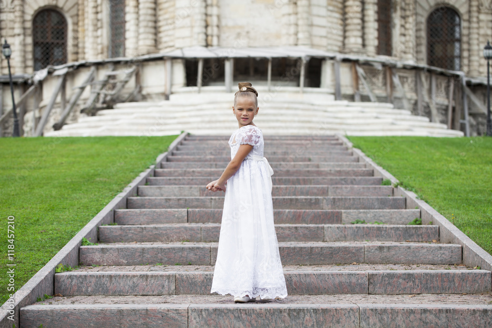 Fototapeta premium Portrait of a beautiful young little girl in white gown