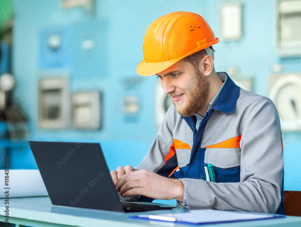 young happy engineer working at laptop in control room young happy engineer working at laptop in control room
