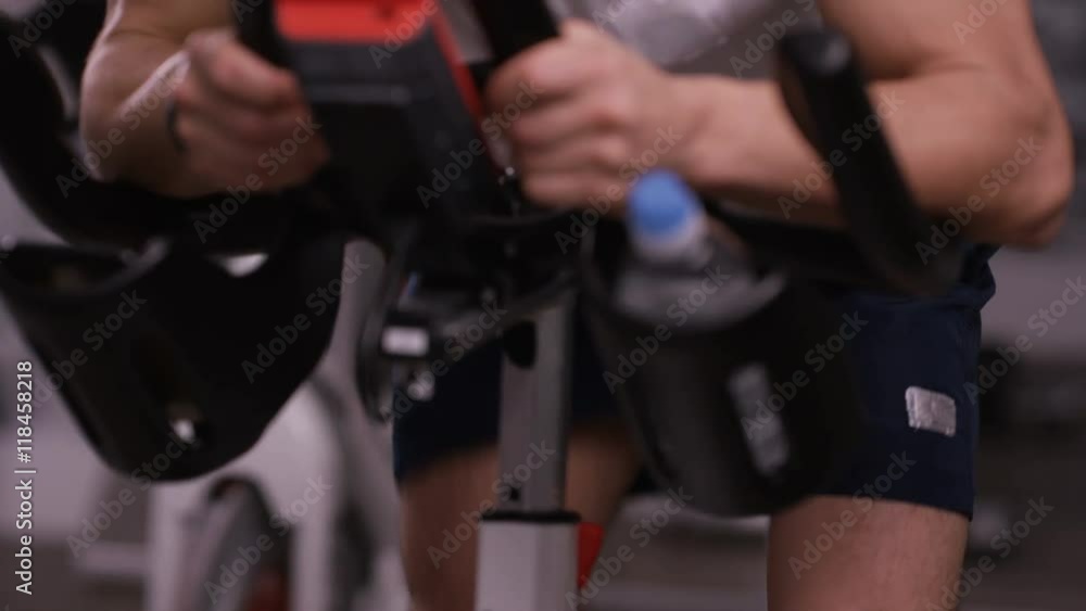 Close up of man working out on exercise bike at the gym Close up of man working out on exercise bike at the gym