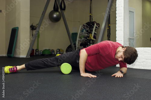 Fitness athletic trainer shows exercises. Handsome man at the gym. Stretching exercises and myofascial relaxation. Sport rehabilitation.