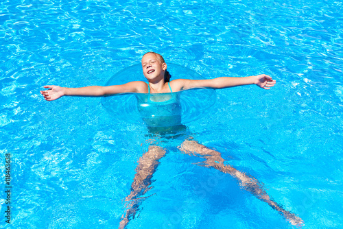 Girl in swimming circle relaxes in pool