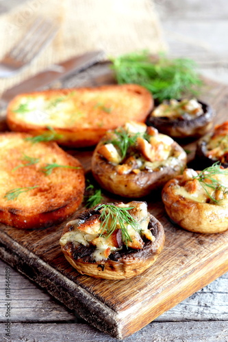 Healthy cheese and meat stuffed mushrooms and fried bread slices on a wooden cutting board. Homemade mushrooms recipe