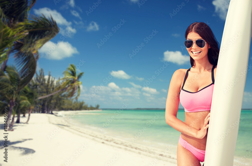 smiling young woman with surfboard on beach