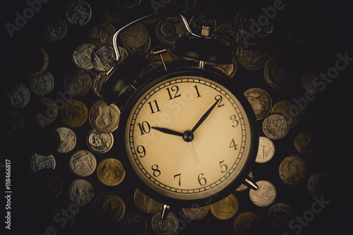 saving time, Alarm clock with coins isolated on black background. with vintage filter