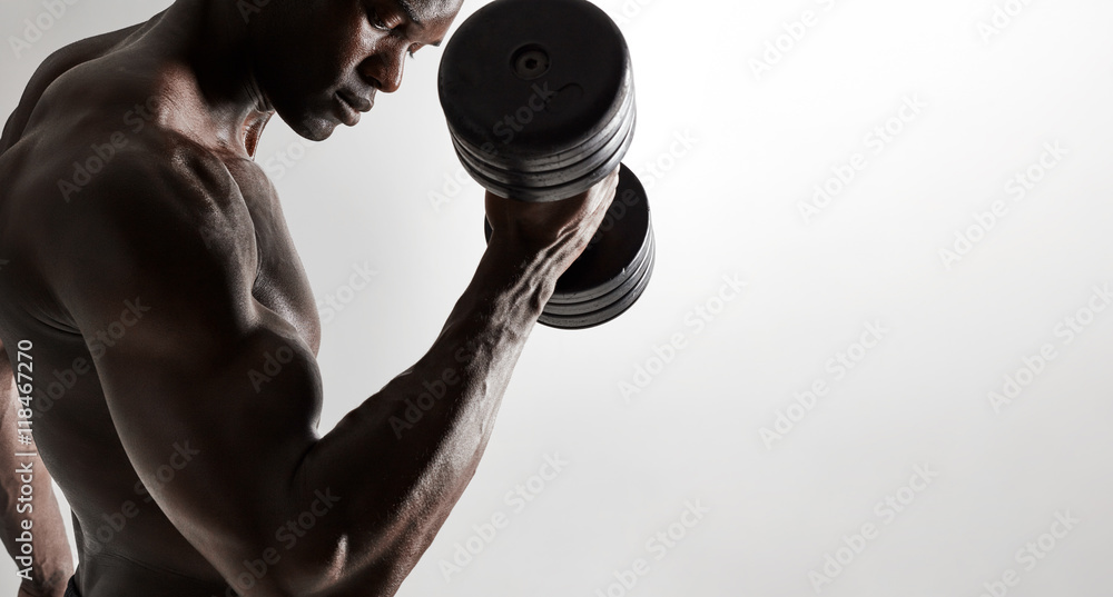 Muscular african male model lifting heavy dumbbells