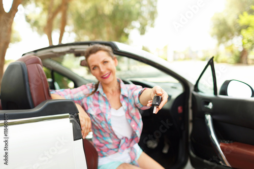 Young pretty woman sitting in a convertible car with the keys in