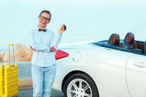 Young woman standing near a convertible with keys in hand © vladstar