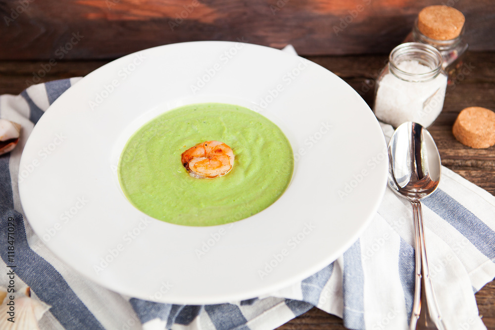 Green Cream of asparagus soup with shrimp in a white bowl on a r Green Cream of asparagus soup with shrimp in a white bowl on a r