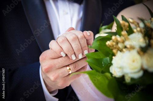 Руки жениха и невесты с кольцами и букетом.