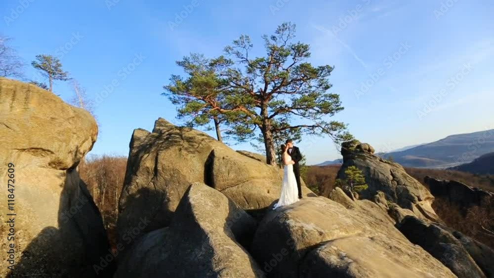 Romantic fairytale couple newlyweds posing at sunset on a background of mountains Romantic fairytale couple newlyweds posing at sunset on a background of mountains