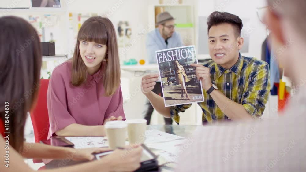 Workers at a fashion magazine discuss ideas in office meeting Workers at a fashion magazine discuss ideas in office meeting