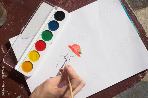 Художник рисует женщину кисточкой и красками на белой бумаге