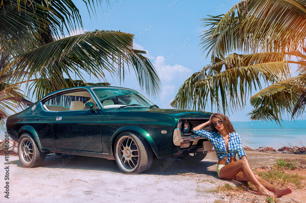 Young attractive model is sitting near the retro car at the beach