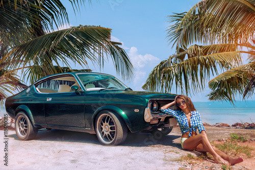 Obraz na płótnie Young attractive model is sitting near the retro car at the beach w salonie