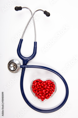 Stethoscope and heart shaped red medical pills