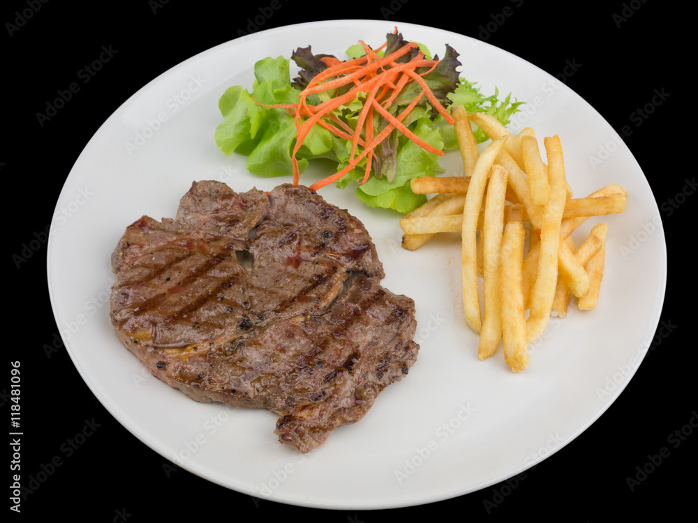 Rib eye steak served with french fries and salads to vegetables isolated on the black background with clipping path Rib eye steak served with french fries and salads to vegetables isolated on the black background with clipping path