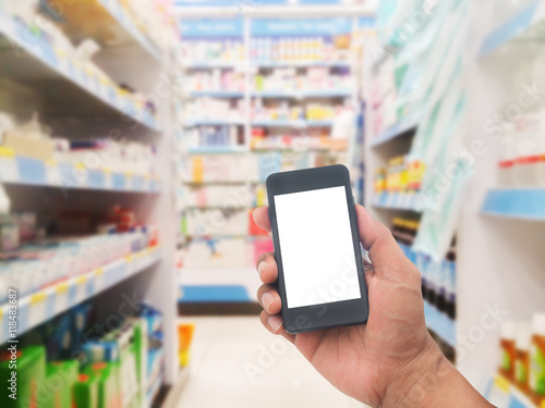 Hand with smartphone on blurred pharmacy store
