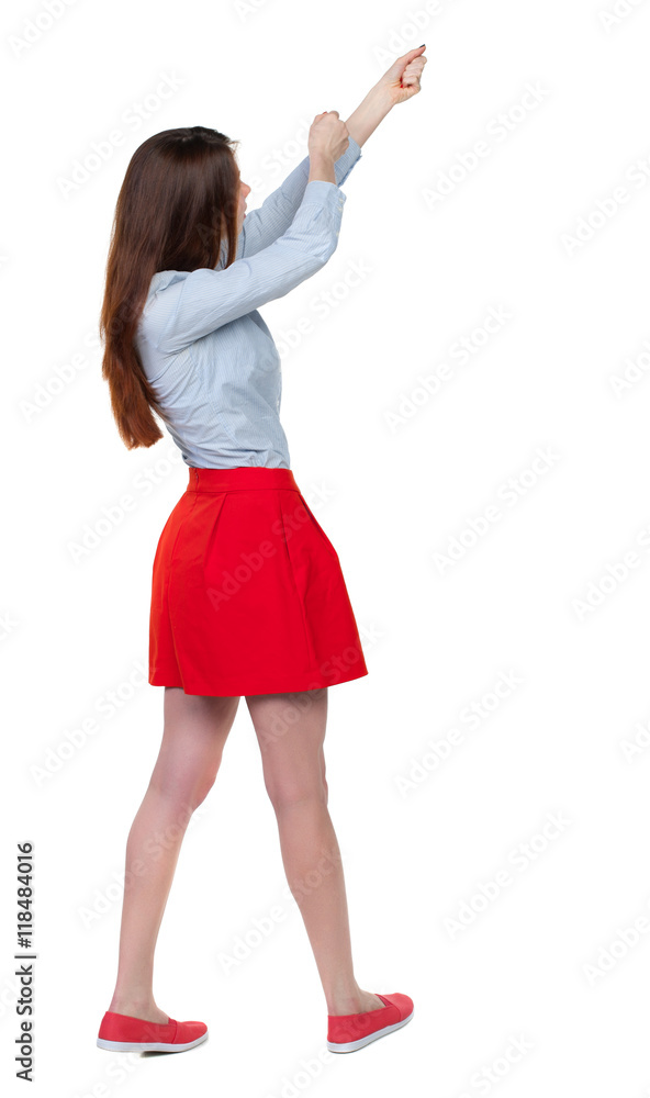 Fototapeta premium back view of standing girl pulling a rope from the top or cling to something. girl watching. Rear view people collection. backside view of person. Isolated over white background. Long-haired