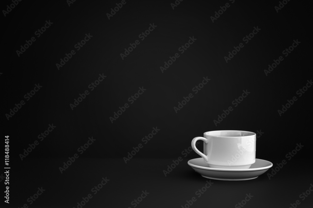White empty ceramic mug from cafe with a saucer are in the corner of a black background. White empty ceramic mug from cafe with a saucer are in the corner of a black background.