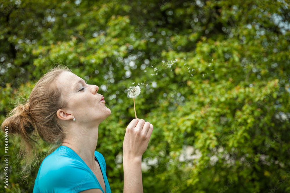 Portrait of young beautiful blonde blowing on a dandelion Portrait of young beautiful blonde blowing on a dandelion