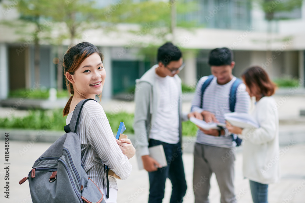 Fototapeta premium Pretty female student with backpack and books