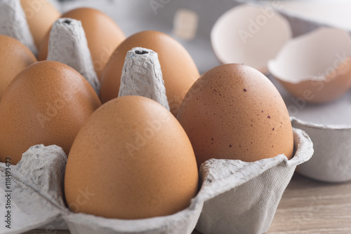 Chicken eggs in the package on a wooden table.