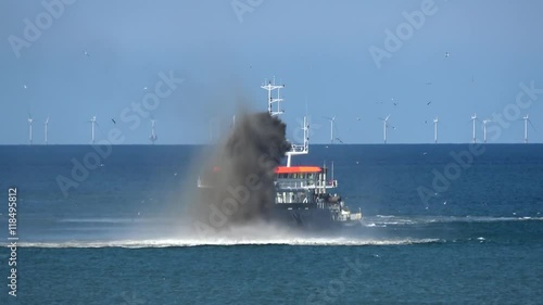 Close up of ship at sea dredging an excavation activity done in shallow water areas for gathering up bottom sediments and disposing of them at different location often used to keep waterways navigable