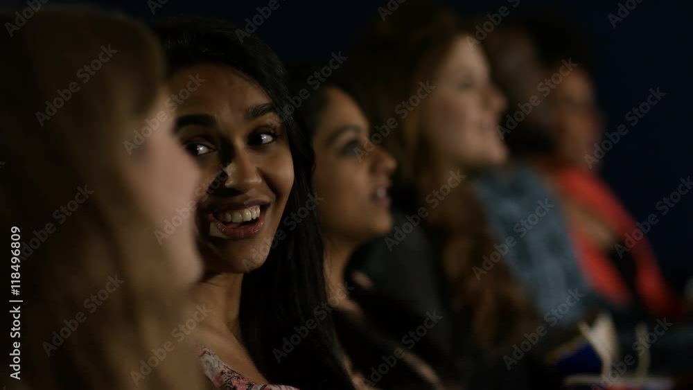 Happy young female friends watching a film with 3D glasses in movie theatre Happy young female friends watching a film with 3D glasses in movie theatre