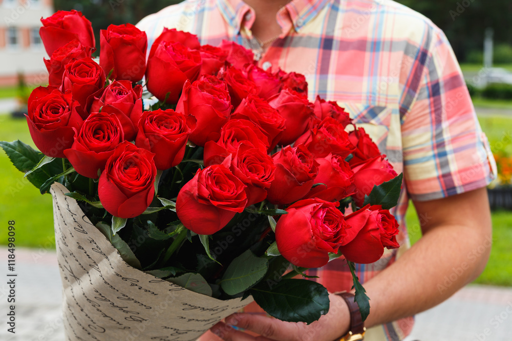 Naklejka premium A man carrying a huge bouquet of red roses