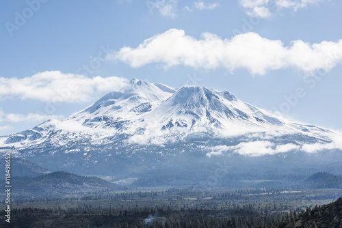 Snowcapped Mount Shasta volcano during winter with valley view and clouds on mountain