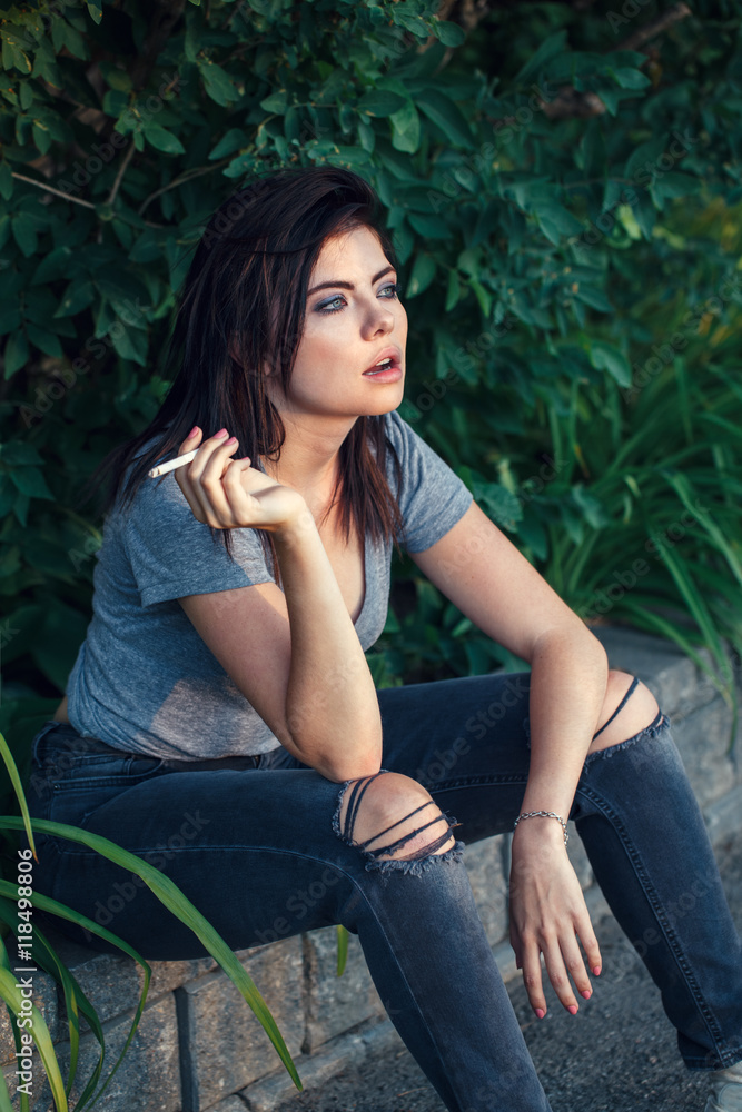 Portrait of white Caucasian beautiful young sexy brunette woman in jeans  and t-shirt outside on sunset smoking cigarette looking away, toned with  Instagram filters, lifestyle concept Stock Photo | Adobe Stock