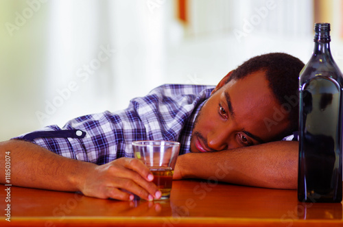 Handsome man wearing white blue shirt sitting by bar counter lying over desk drunk sleeping, alcoholic concept