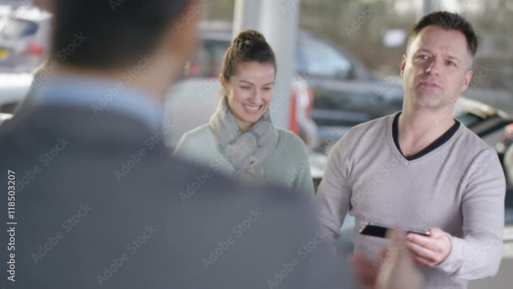 Happy couple buying new car ask salesman to take their picture Happy couple buying new car ask salesman to take their picture
