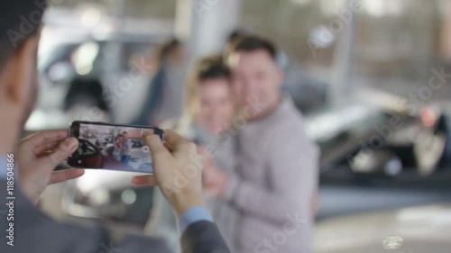  Happy couple buying new car ask salesman to take their picture