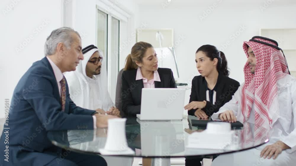 Western businesswomen negotiating in meeting with middle eastern businessmen Western businesswomen negotiating in meeting with middle eastern businessmen