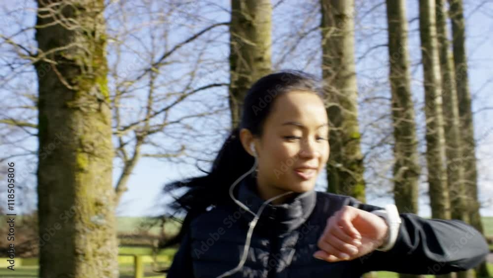Young woman running in the countryside stops to look at watch Young woman running in the countryside stops to look at watch