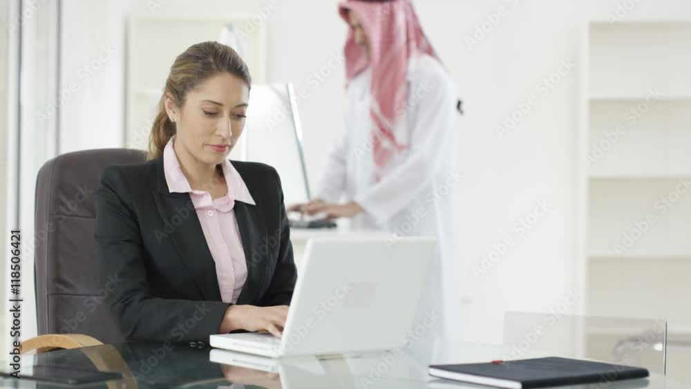 Portrait smiling Western businesswoman with Arabic businessman in background Portrait smiling Western businesswoman with Arabic businessman in background