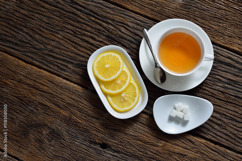 Top view of cup of tea with sugar cube and lemon on wooden table Top view of cup of tea with sugar cube and lemon on wooden table