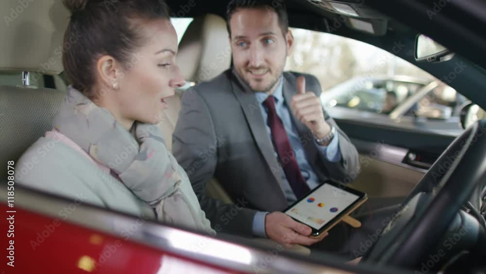 Salesman in car dealership showing customer the interior of new car Salesman in car dealership showing customer the interior of new car