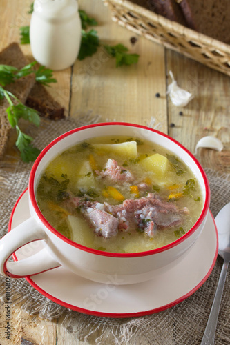 Delicious soup with rice and chunks of meat, rye bread on a wood photo