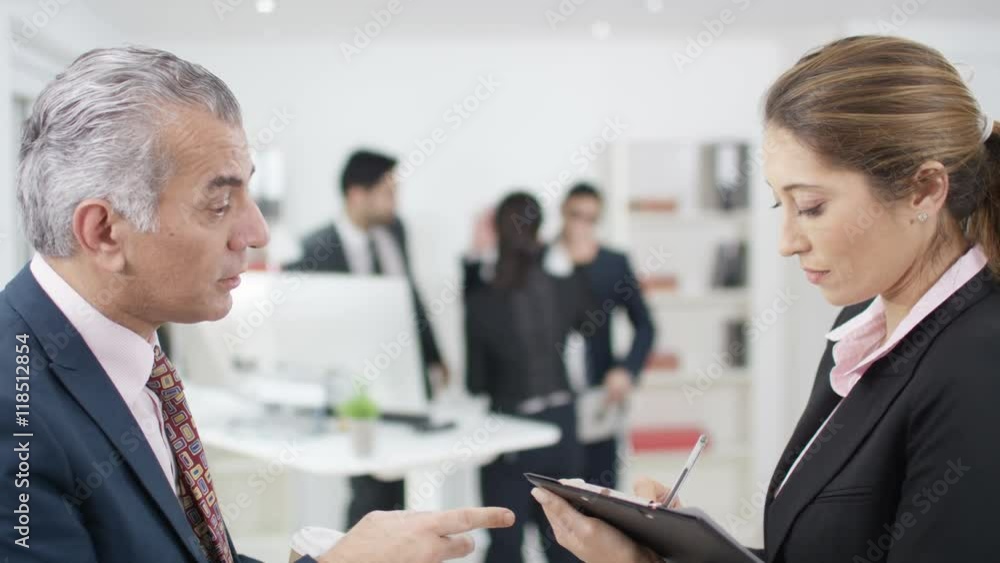 Arab businessman giving instructions to his personal assistant in office Arab businessman giving instructions to his personal assistant in office