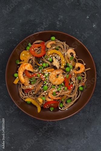 Buckwheat noodles with seafood in a bowl on dark background
