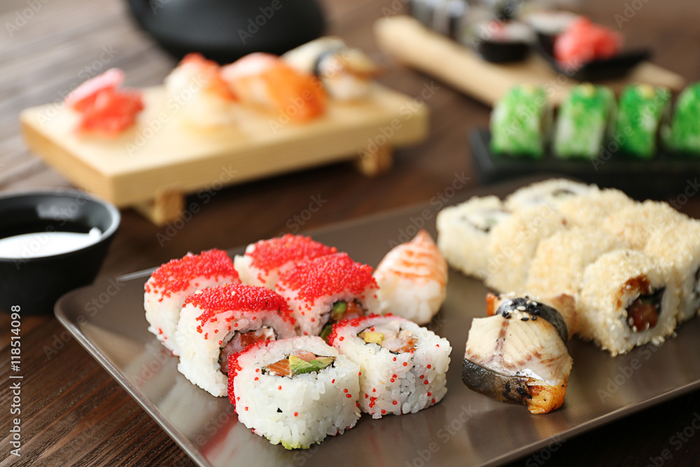 Delicious sushi set on ceramic plate and wooden boards Delicious sushi set on ceramic plate and wooden boards