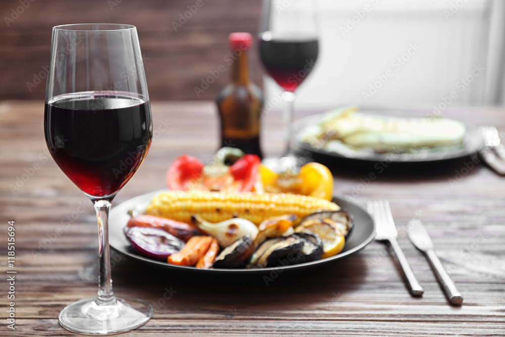 Grilled vegetables and glass of wine on wooden table