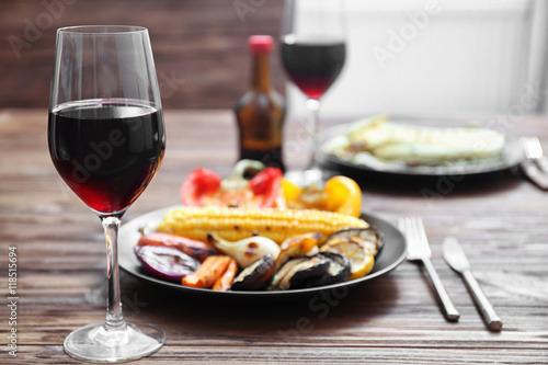 Grilled vegetables and glass of wine on wooden table