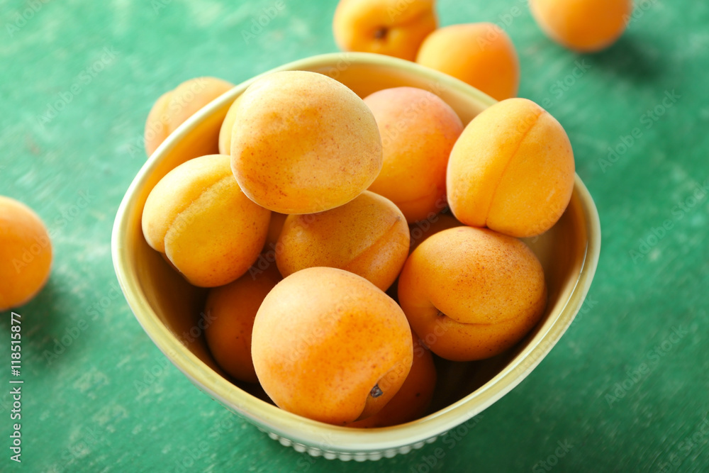 Heap of apricots in bowl on green table Heap of apricots in bowl on green table