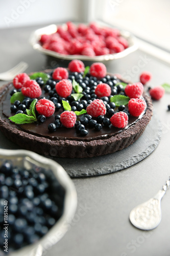 Delicious chocolate tart with berries on grey table